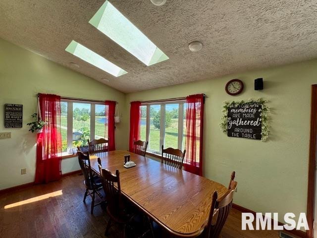 dining space featuring a textured ceiling, dark hardwood / wood-style flooring, and lofted ceiling with skylight