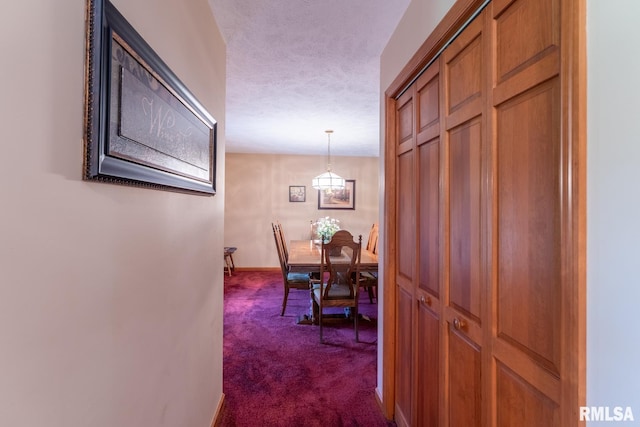 corridor with dark colored carpet and a textured ceiling