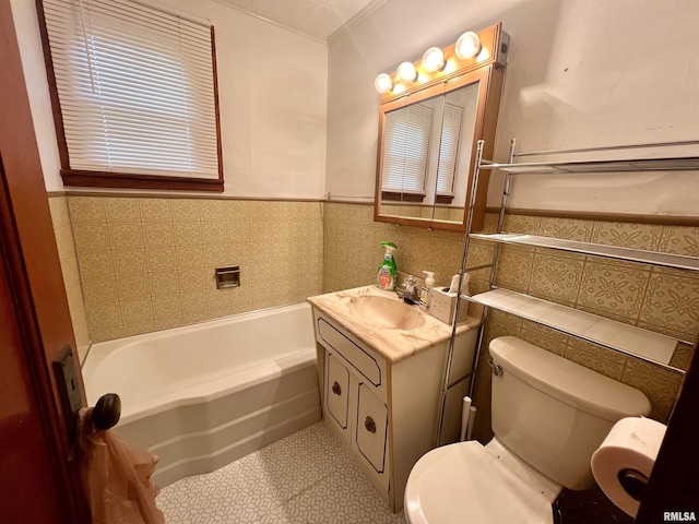 bathroom featuring a bathtub, a wainscoted wall, tile walls, toilet, and vanity