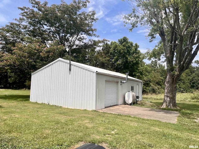 view of outdoor structure featuring a garage, concrete driveway, and an outbuilding