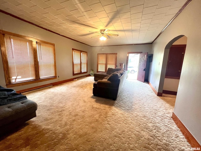 carpeted living room with arched walkways, ornamental molding, baseboard heating, and baseboards