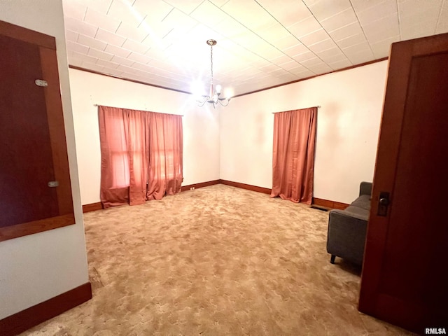 empty room with ornamental molding, baseboards, and an inviting chandelier