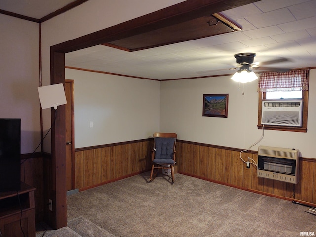 sitting room with heating unit, wood walls, light carpet, ornamental molding, and ceiling fan