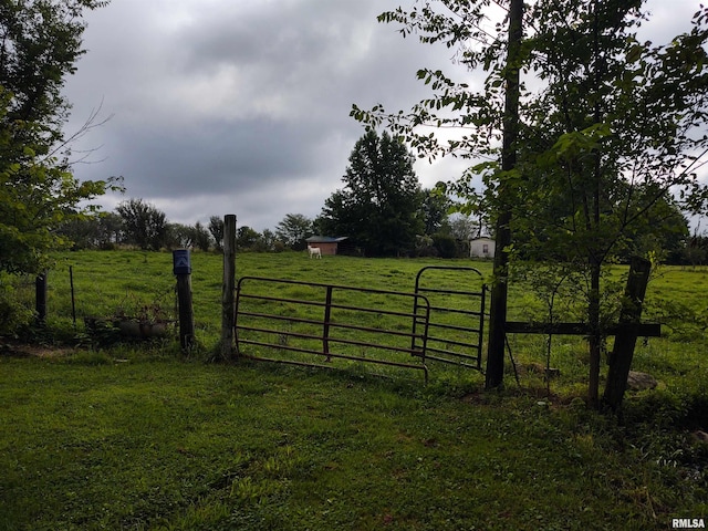 view of gate with a rural view and a yard