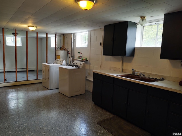 kitchen with a baseboard radiator, sink, washing machine and clothes dryer, and a wealth of natural light