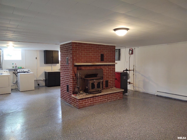 interior space featuring a brick fireplace, baseboard heating, a wood stove, and washing machine and clothes dryer