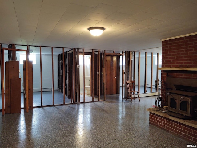 unfurnished living room with a baseboard heating unit, a wood stove, and a fireplace