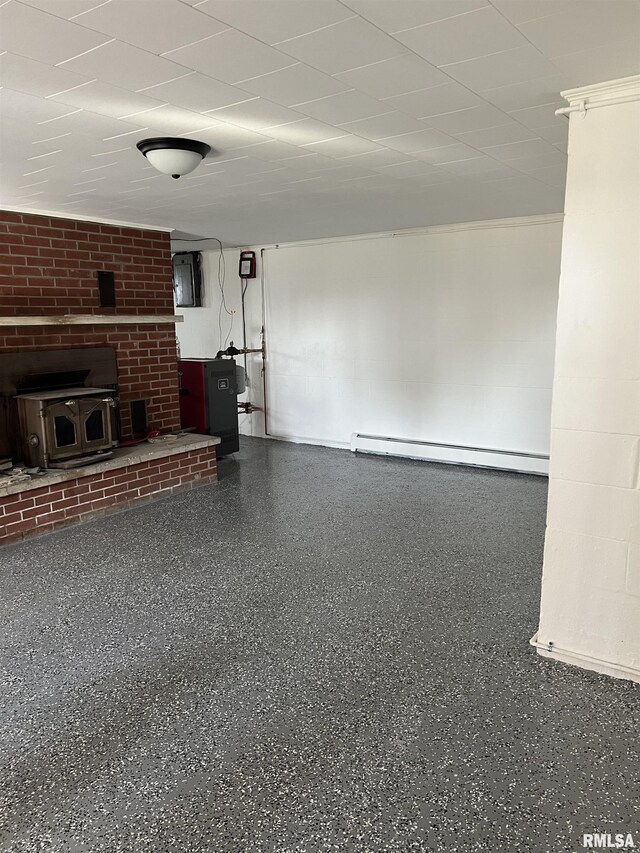 unfurnished living room with a brick fireplace, a wood stove, and a baseboard heating unit