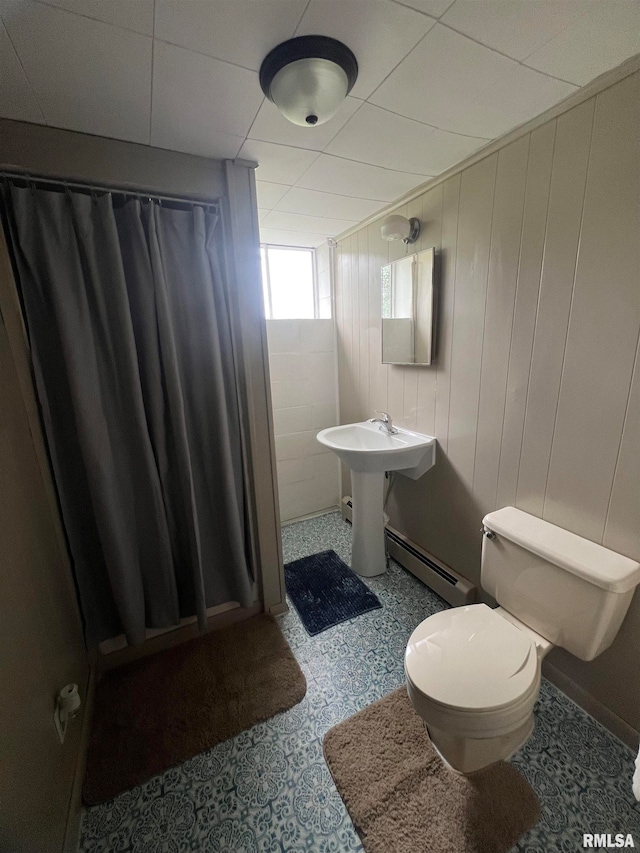 bathroom featuring a baseboard radiator, wood walls, toilet, and curtained shower