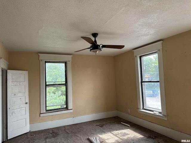 unfurnished room featuring plenty of natural light, a textured ceiling, ceiling fan, and carpet flooring