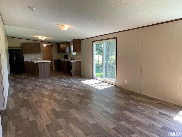 kitchen with a center island, sink, black fridge, dark hardwood / wood-style flooring, and vaulted ceiling