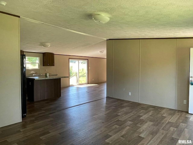 unfurnished living room featuring vaulted ceiling, dark hardwood / wood-style floors, and a textured ceiling