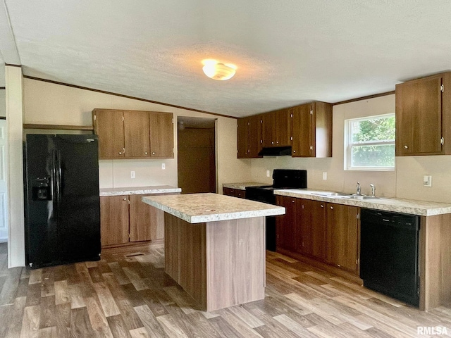 kitchen featuring a center island, black appliances, sink, vaulted ceiling, and light hardwood / wood-style floors