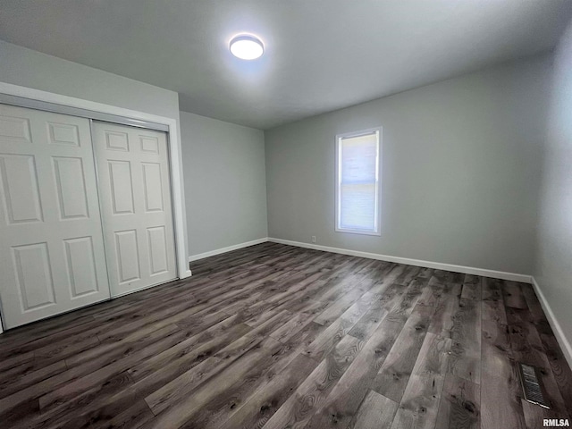 unfurnished bedroom featuring a closet and dark hardwood / wood-style flooring