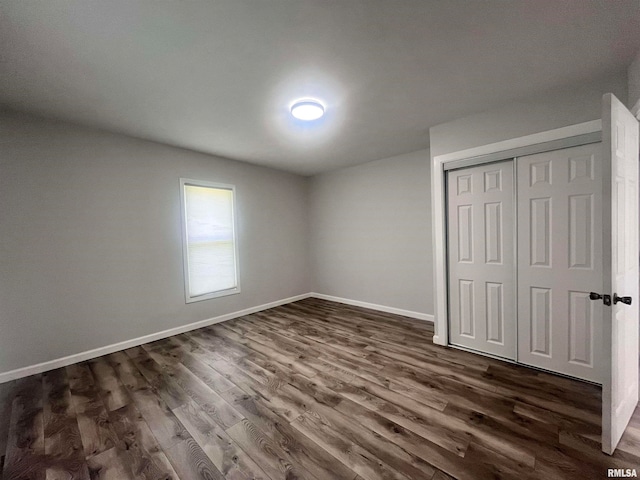 unfurnished bedroom with dark hardwood / wood-style flooring and a closet