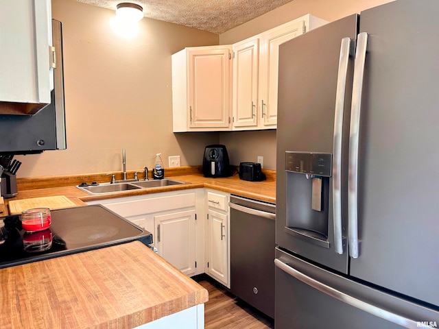 kitchen with stainless steel appliances, white cabinetry, a textured ceiling, and sink