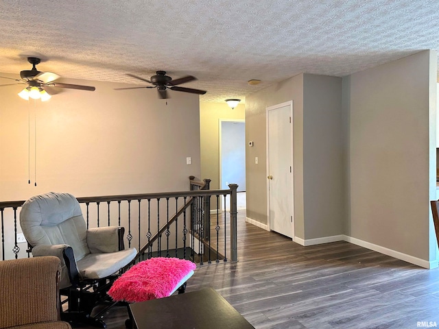 living area featuring ceiling fan, a textured ceiling, and dark hardwood / wood-style flooring