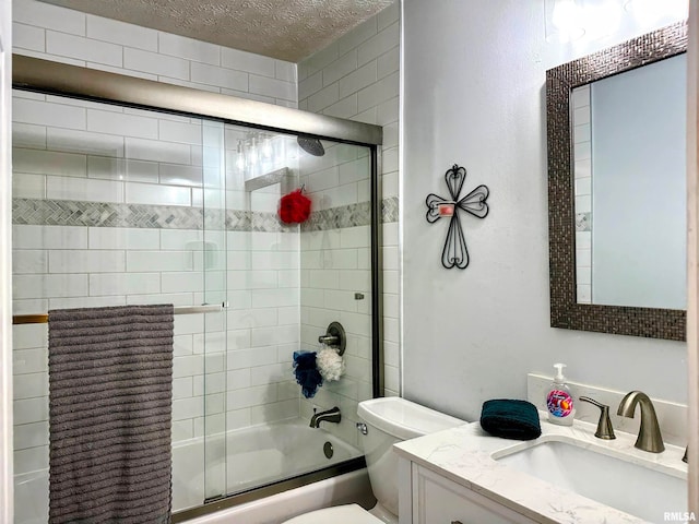 full bathroom with vanity, a textured ceiling, enclosed tub / shower combo, and toilet