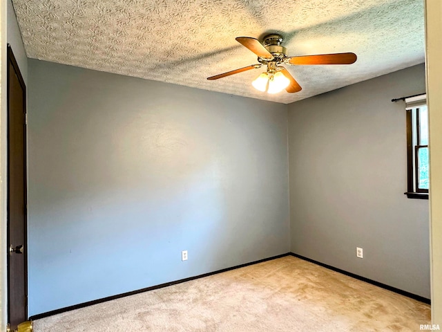 empty room with ceiling fan, light colored carpet, and a textured ceiling