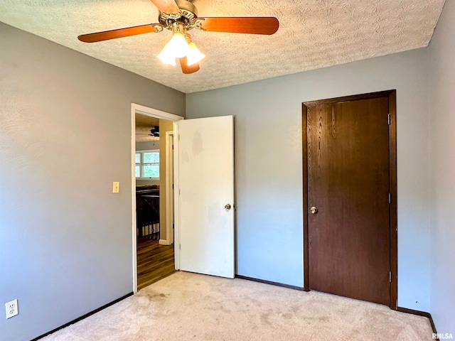 unfurnished bedroom with light carpet, a closet, a textured ceiling, and ceiling fan