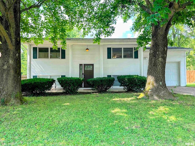 raised ranch featuring a garage and a front lawn