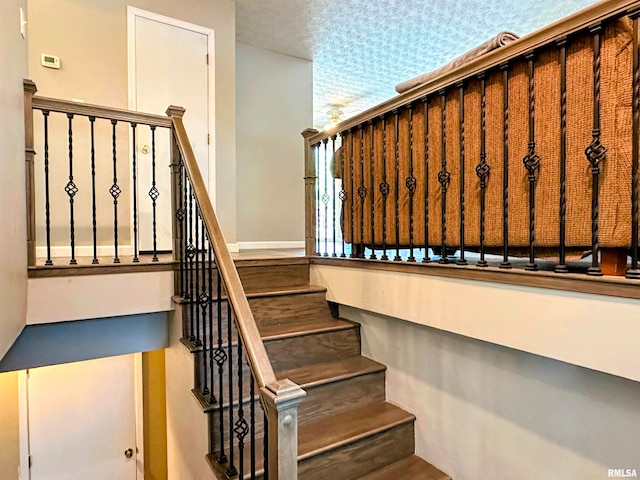 stairway featuring a textured ceiling