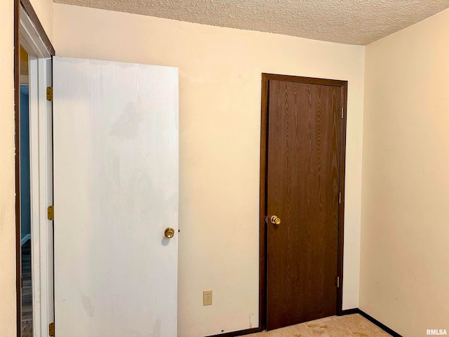 unfurnished bedroom with light colored carpet, a textured ceiling, and a closet