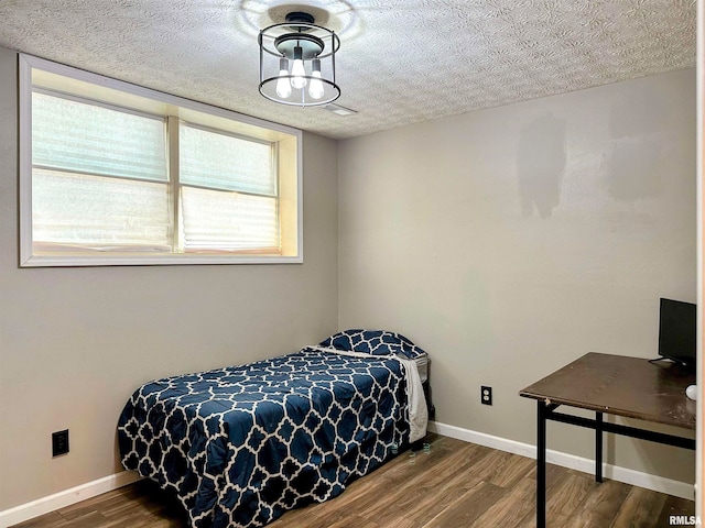 bedroom with multiple windows, a textured ceiling, and hardwood / wood-style flooring