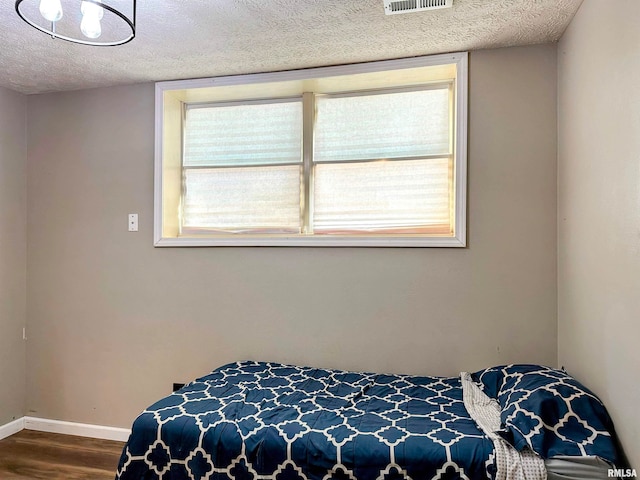 bedroom with wood-type flooring, multiple windows, and a textured ceiling