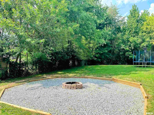 view of yard with a trampoline and an outdoor fire pit