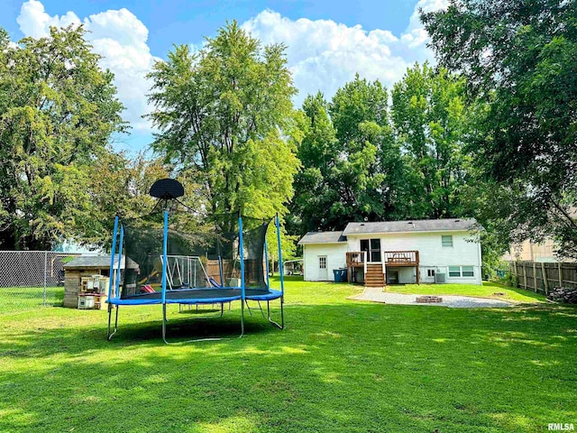 view of yard featuring a trampoline and a deck