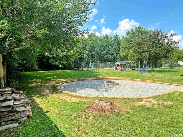 view of yard with a playground, a fire pit, and a trampoline