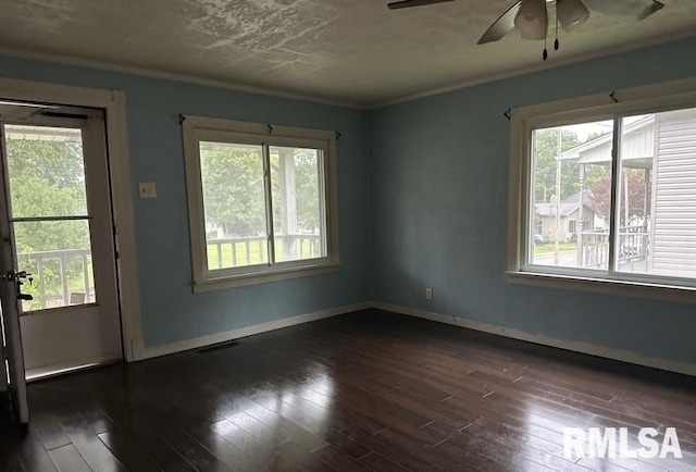 empty room with dark hardwood / wood-style flooring, crown molding, a wealth of natural light, and ceiling fan