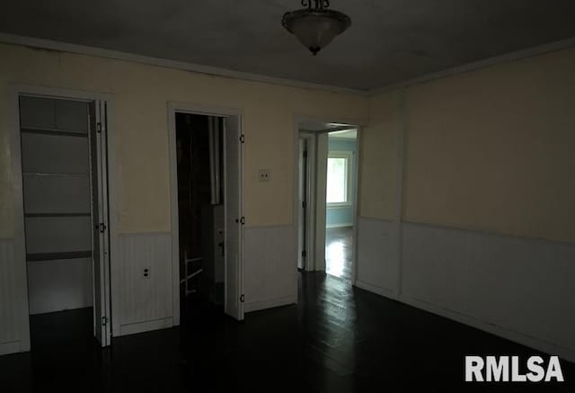 spare room featuring ornamental molding and dark wood-type flooring