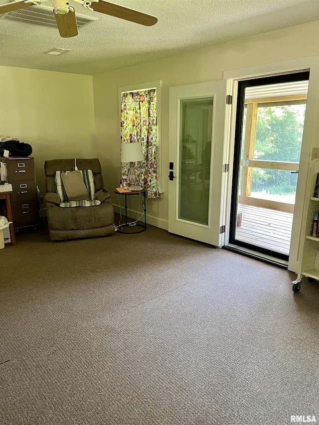 living room with carpet flooring, a textured ceiling, and ceiling fan