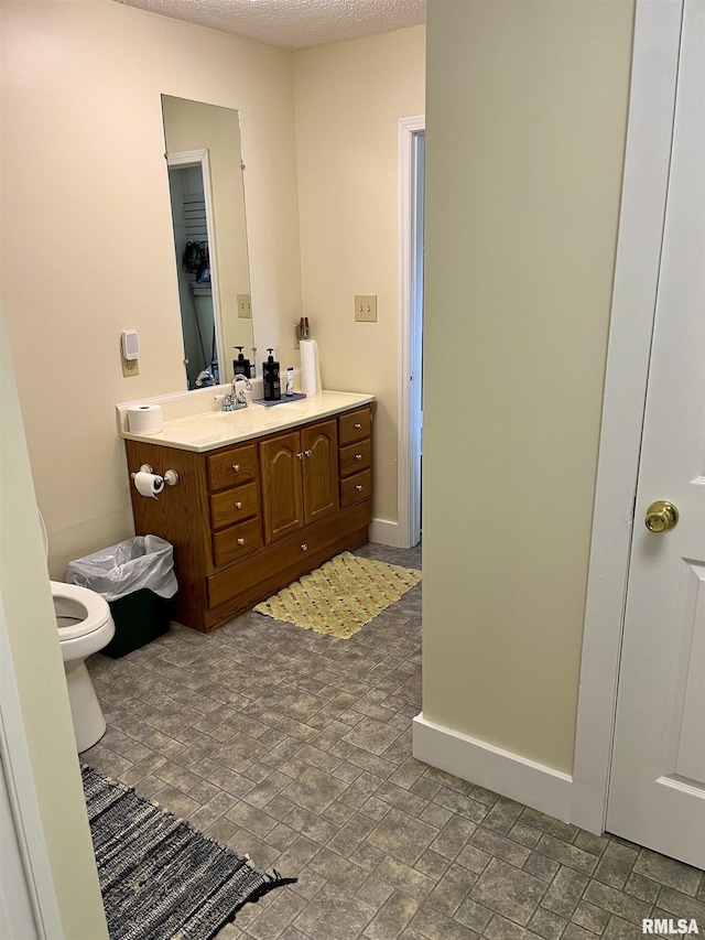 bathroom featuring vanity, toilet, and a textured ceiling