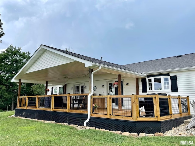 back of property with roof with shingles, a lawn, and a wooden deck