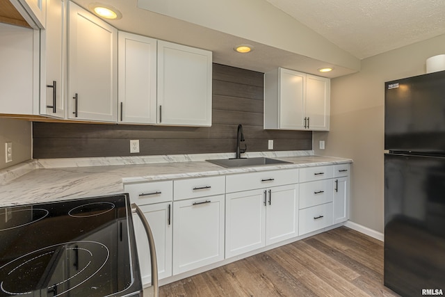 kitchen featuring lofted ceiling, sink, white cabinets, and black appliances