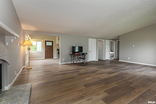 unfurnished living room featuring dark wood-type flooring and a tiled fireplace