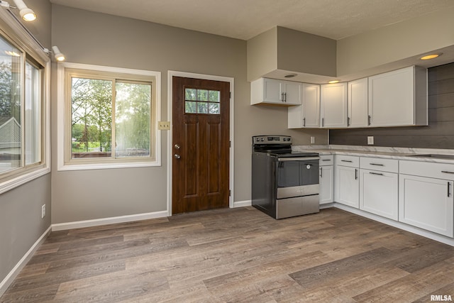 kitchen featuring stainless steel electric range oven, sink, white cabinets, and light hardwood / wood-style floors