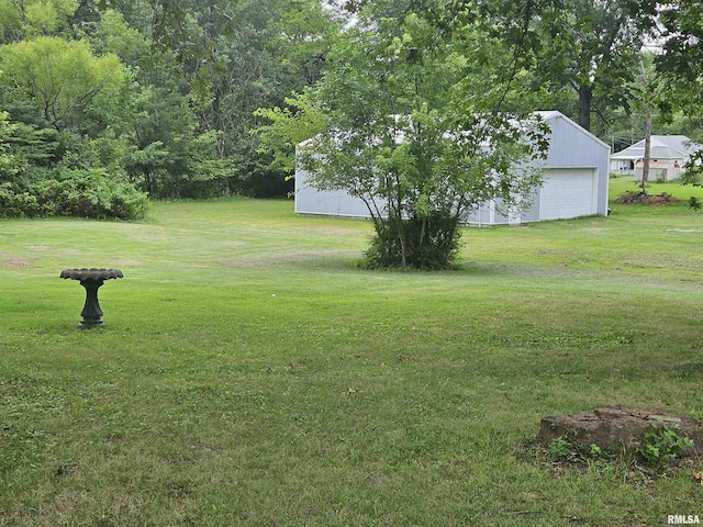 view of yard with a garage and an outbuilding