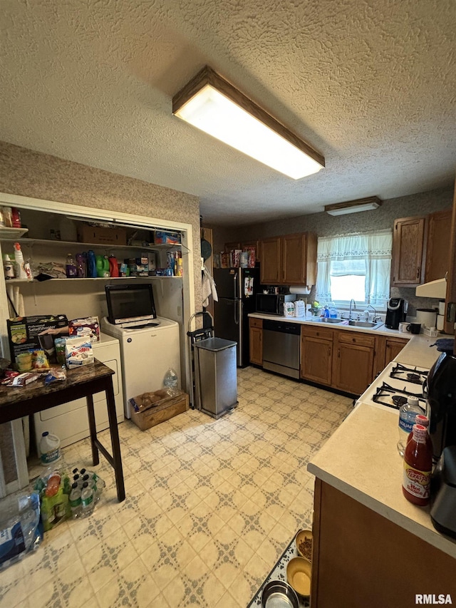 kitchen featuring black appliances, sink, a textured ceiling, and independent washer and dryer