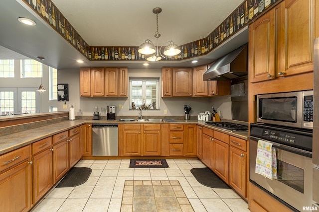 kitchen featuring sink, appliances with stainless steel finishes, light tile patterned flooring, decorative light fixtures, and wall chimney exhaust hood