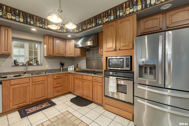 kitchen with wall chimney range hood, sink, stainless steel appliances, light tile patterned flooring, and a chandelier