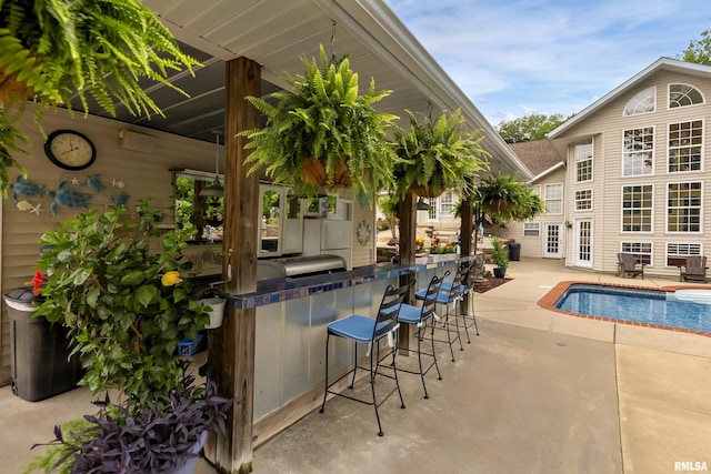 view of pool featuring area for grilling, an outdoor bar, and a patio