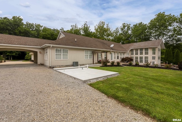 rear view of house with a carport, a yard, and central air condition unit