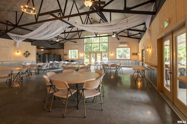 dining space with plenty of natural light, high vaulted ceiling, and wood walls