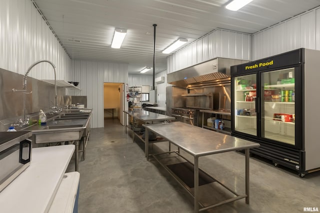 kitchen featuring stainless steel appliances, concrete floors, and wall chimney range hood