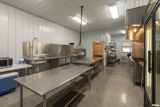 kitchen with sink, decorative light fixtures, stainless steel counters, concrete floors, and premium appliances