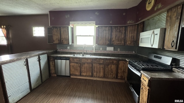 kitchen with sink, dark brown cabinets, stainless steel appliances, dark hardwood / wood-style floors, and a textured ceiling